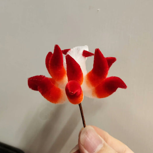 Close-up of handmade Ronghua red-orange nine-tailed fox hairpin in mulberry silk velvet, held in hand