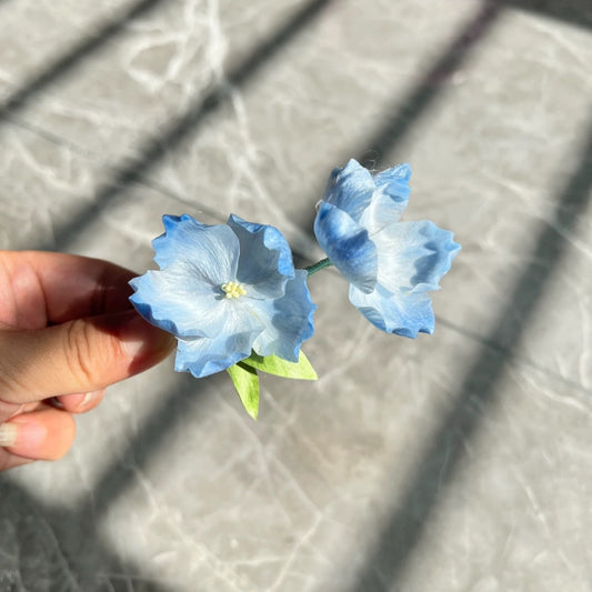 Handmade Ronghua blue starflower brooch in mulberry silk velvet – double flower with green leaf, held in hand