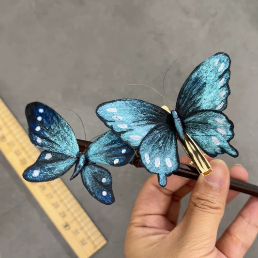 Handmade Ronghua blue butterfly hairpin – single large and small size in mulberry silk velvet with moving wings on wooden hair stick, held in hand