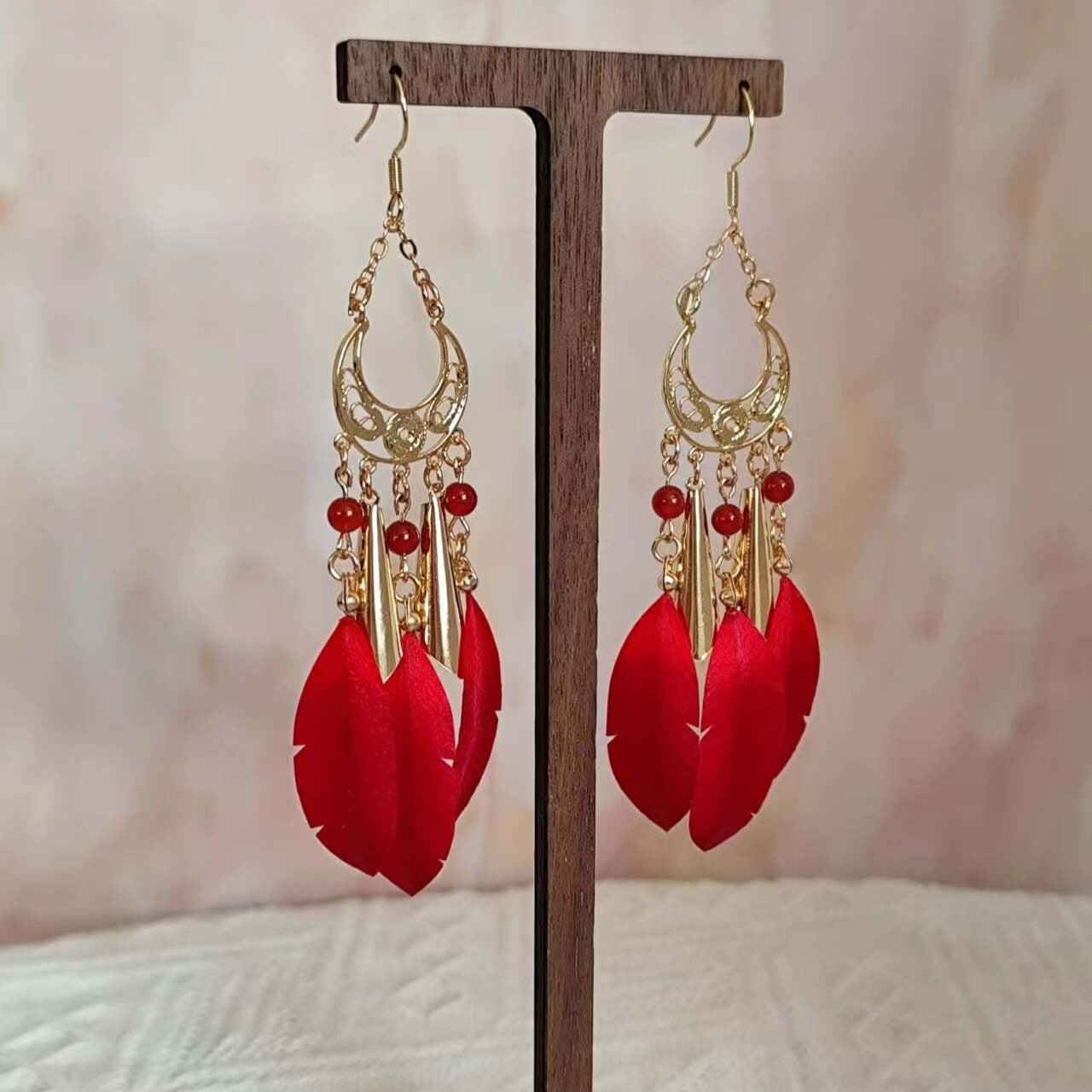 Handmade Ronghua red feather tassel earrings in mulberry silk velvet with gold filigree and agate beads on display stand
