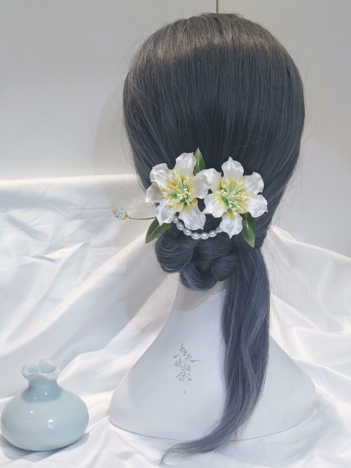 Handmade Ronghua double lily hairpin in white mulberry silk velvet with green leaves and pearl details worn in low bun