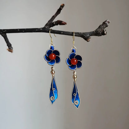 Handmade Ronghua blue filigree drop earrings in mulberry silk velvet with red agate and gold details hanging on branch