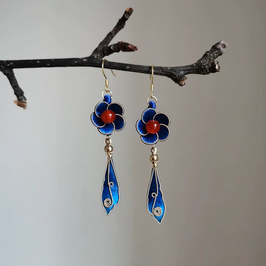 Handmade Ronghua blue filigree drop earrings in mulberry silk velvet with red agate and gold details hanging on branch