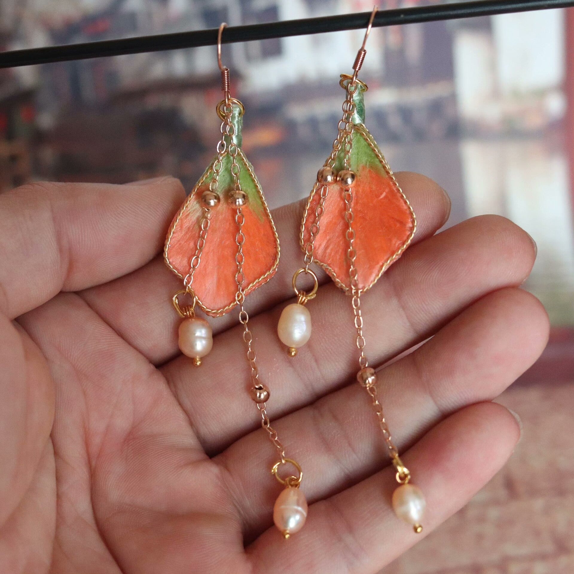 Handmade Ronghua orange-green silk velvet leaf long drop earrings with pearl chain and gold details hanging on display