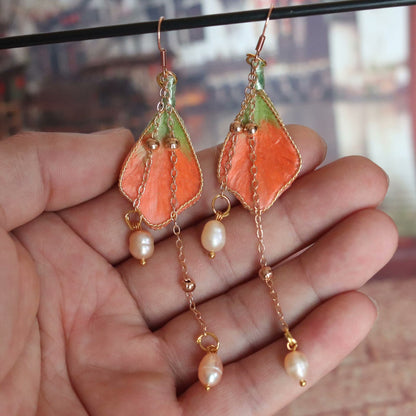 Handmade Ronghua orange-green silk velvet leaf long drop earrings with pearl chain and gold details hanging on display