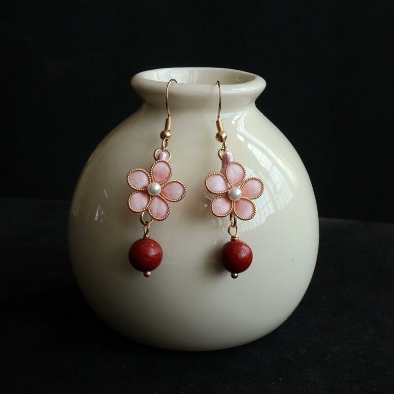 Handmade Ronghua pink peach blossom drop earrings in mulberry silk velvet with incense pearl and gold details displayed on white vase