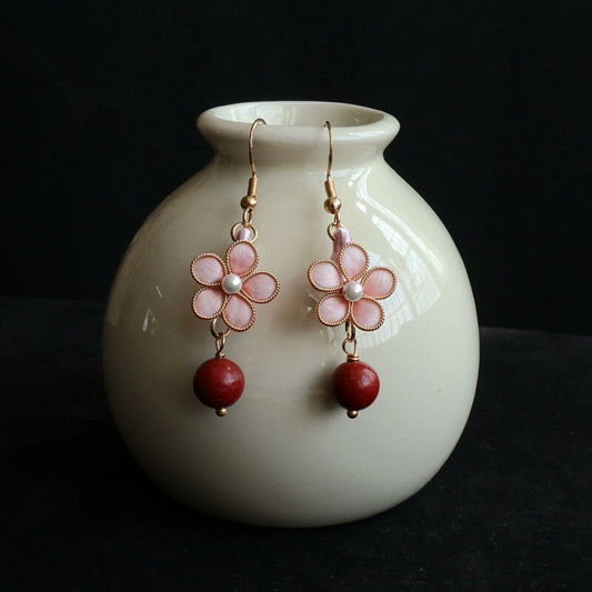 Handmade Ronghua pink peach blossom drop earrings in mulberry silk velvet with incense pearl and gold details displayed on white vase