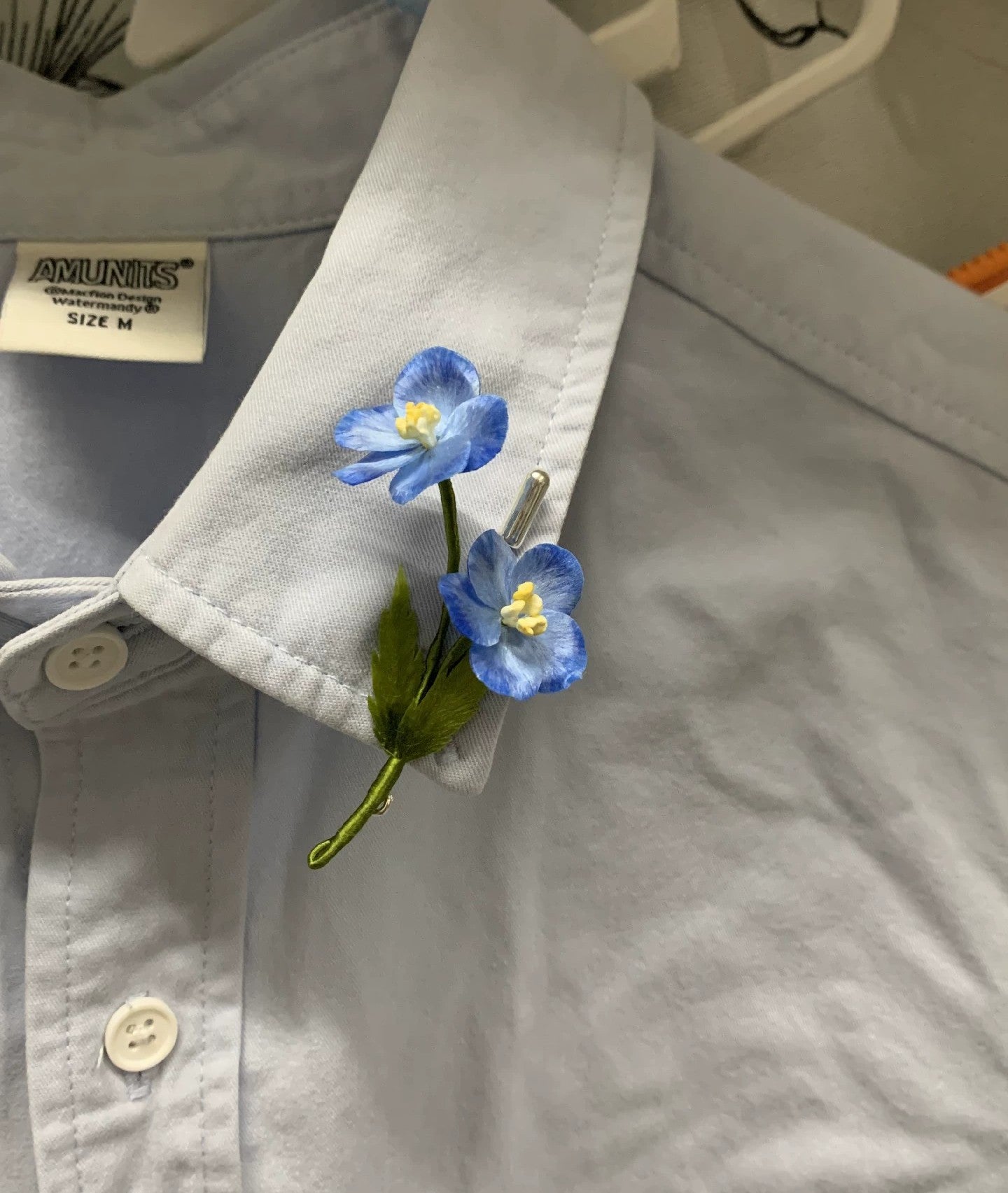 Close-up of sky-blue Ronghua silk star flowers with white edges and green leaf on stick pin