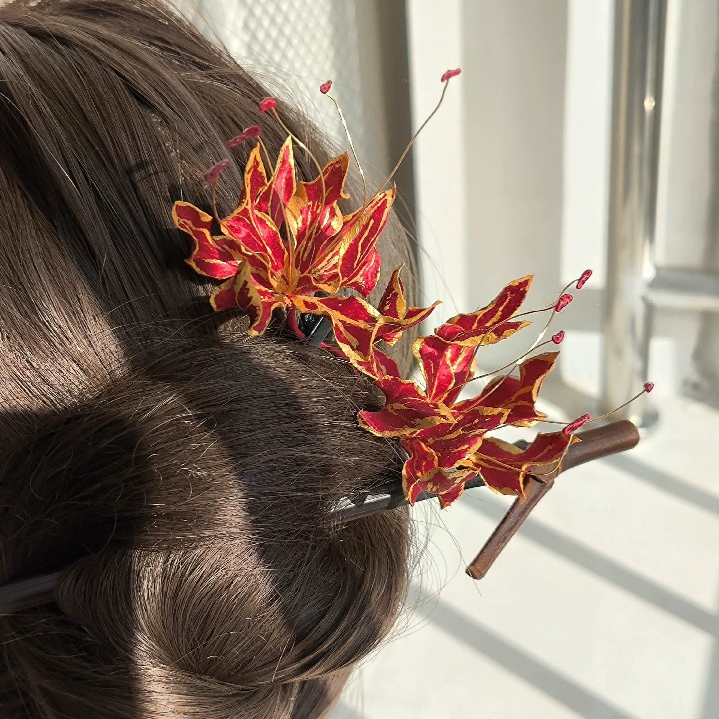 Close-up of vibrant red petals with golden edges and curling stamens on Ronghua silk gloriosa lily