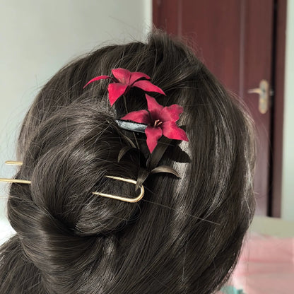 Close-up of rich crimson Ronghua silk lilies with bronze-green leaves on black hairpin
