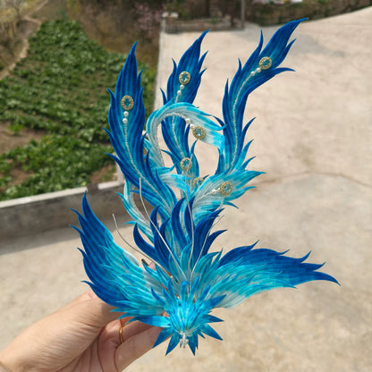 Handmade Ronghua blue phoenix ornament with layered silk velvet feathers, pearls and crystal accents held in hand outdoors