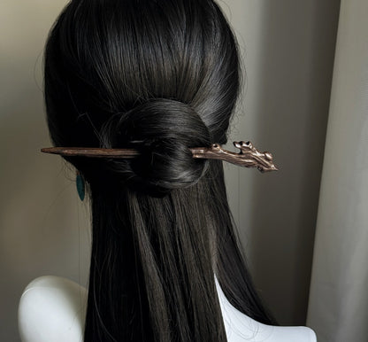 Rear view of long dark hair in a low bun secured with natural rosewood hair stick featuring branch design