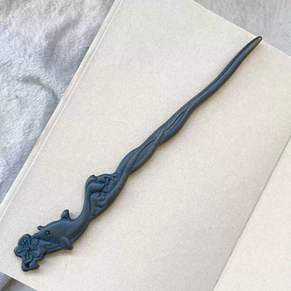Natural Green Sandalwood hair stick with blue whale carving 20cm on open book background.