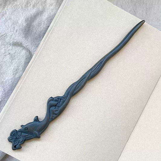 Natural Green Sandalwood hair stick with blue whale carving 20cm on open book background.